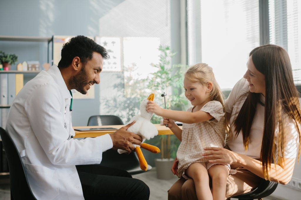 Happy little girl, mother and family doctor playing fun game with toy and neurologist's hammer.